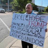 Rosendo DelGado holds his anti-Trump sign during a protest over a visit by U.S. Republican presidential candidate Donald Trump to an African-American church in Detroit Saturday. | REUTERS