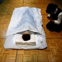 A funeral undertaker prays next to a model during an ceremonial nōkan (encoffining) competition at Life Ending Industry EXPO 2017 in Tokyo on Thursday. | REUTERS