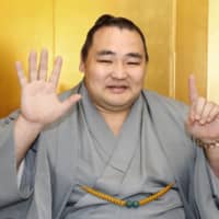 Yokozuna Kakuryu holds up six fingers to celebrate his sixth Emperor\'s Cup win during a Monday new conference in Nagoya. | KYODO