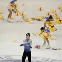 Yuzuru Hanyu acknokwledges the crowd as flower girls collect toys and flowers thrown by fans at Makomanai Ice Arena. | AP