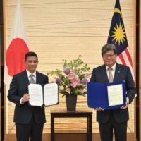 Senior Minister of Malaysia’s Ministry of International Trade and Industry Mohamed Azmin Ali exchanges an agreement on aircraft industry cooperation with Japan’s former Minister of Economy, Trade and Industry Koichi Hagiuda on May 27. | MINISTRY OF INTERNATIONAL TRADE AND INDUSTRY