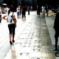 Tourists look at bronzed impressions of the feet of some of the people who survived the invasion. | AP PHOTO