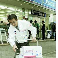 A post office worker collects Japan Post Yu-Pack parcels from a Lawson Inc. convenience store in Shinagawa Ward, Tokyo. | TAIGA URANAKA PHOTO