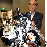 Honda Motor Co. Senior Managing Director Motoatsu Shiraishi shows off a newly developed hybrid engine in Tokyo that will debut in an all-new Civic Hybrid scheduled to be launched this autumn. | JAPAN AEROSPACE EXPLORATION AGENCY PHOTO/KYODO