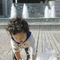 T-shirt weather: A child plays with water at a park in Shizuoka on Saturday. | KYODO PHOTO
