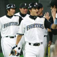 Hokkaido Nippon Ham Fighters shortstop Makoto Kaneko (right) celebrates hitting a two-run home run against the Seibu Lions on Tuesday at Sapporo Dome. The Fighters clinched their third Pacific League title in four years after the second-place Tohoku Rakuten Eagles lost to the Chiba Lotte Marines. | KYODO PHOTO