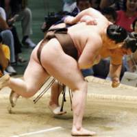 Building momentum: Yokozuna Hakuho throws fourth-ranked maegashira Wakanosato on Monday to continue his unbeaten run at the Nagoya Grand Sumo Tournament at Aichi Prefectural Gymnasium. | KYODO PHOTO