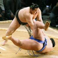 Powerful move: Yokozuna Asashoryu shoves Kotoshogiku to the clay surface on Friday. | KYODO PHOTO