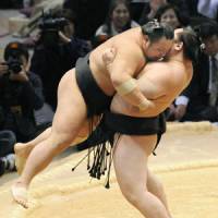 A little heavy lifting: Asashoryu picks up Chiyotaikai during their bout at the Kyushu Grand Sumo Tournament on Tuesday. | KYODO PHOTO