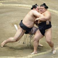 Winning form: Asashoryu (left) forces Takekaze out of the raised ring Tuesday in the New Year Grand Sumo Tournament. | KYODO PHOTO
