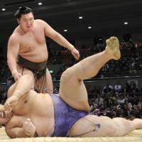 Still unbeaten: Hakuho (13-0) overpowers ozeki Kaio on Friday in the Spring Grand Sumo Tournament in Osaka. | KYODO PHOTO