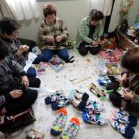 Elderly women making sandals from used T-shirts in a small room of a temporary housing complex in Ishinomaki, Miyagi Prefecture, on March 3, 2014.  | AFP-JIJI