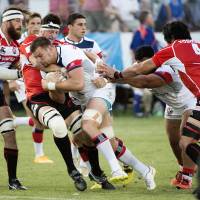 Cameron Dolan (center) of the United States is challenged by Japan\'s players during a Pacific Nations Cup match on Friday in Sacramento, California. The U.S. defeated Japan 23-18. | AFP-JIJI