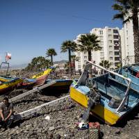 Fishing boats run aground by the sea line the beach Thursday in Coquimbo, some 445 km north of Santiago, after being hit by tsunami after Wednesday\'s quake off Chile. Japan is bracing for tsunami to reach its Pacific shores early Friday. | AFP-JIJI