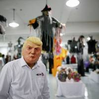 The manager of Jinhua Partytime Latex Art and Crafts Factory wears a mask of U.S. Republican presidential candidate Donald Trump as he presents products to reporters at his factory\'s showroom in Jinhua, China, on Wednesday. | REUTERS