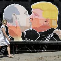 A pedestrian eyes a graffiti mural depicting U.S. Republican presidential hopeful Donald Trump and Russian President Vladimir Putin in Vilnius on June 1. | REUTERS