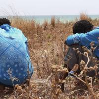 Filmon Selomon (left) and Mabtom Tekle conceal their faces during an interview with AP in Pozzallo, Sicily, May 29. The two Eritreans survived an accident that might have produced the largest number of missing and presumed dead, when a wooden fishing boat being towed by another smugglers\' boat from the Libyan port of Sabratha, sank May 28. | AP