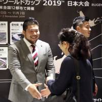 Japan prop Kensuke Hatakeyama shakes hands with a fan at a 2019 Rugby World Cup countdown event in Tokyo on Tuesday. | KYODO