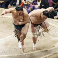 Okinoumi (left) and Terunofuji fall out of the ring during their bout on the fourth day of the Autumn Grand Sumo Tournament on Wednesday. | KYODO