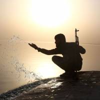 A member of the U.S.-backed Syrian Democratic Forces, made up of an alliance of Arab and Kurdish fighters, splashes water at the Tabqa dam in Syria on Saturday. | AFP-JIJI