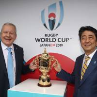 Prime Minister Shinzo Abe and World Rugby chairman Bill Beaumont pose with the William Webb Ellis Cup during the 2019 Rugby World Cup draw on Wednesday in Kyoto. | AFP-JIJI