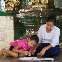 A girl does homework with her mother in Yangon. With help from Japan, Myanmar has introduced a new curriculum for first-graders. | KYODO