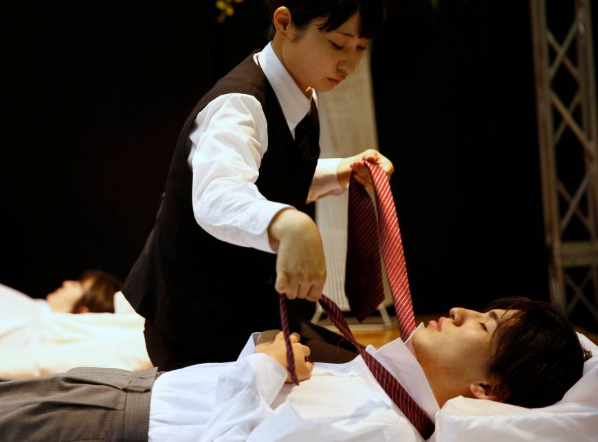 A funeral undertaker dresses a model during an encoffinment competition at Life Ending Industry EXPO 2017 in Tokyo.