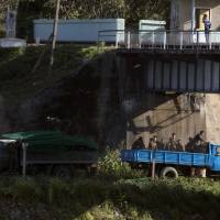 North Korean soldiers work on a fence along the banks of North Korea across from the Chinese border town of Jian in northeastern China's Jilin province in August. | AP