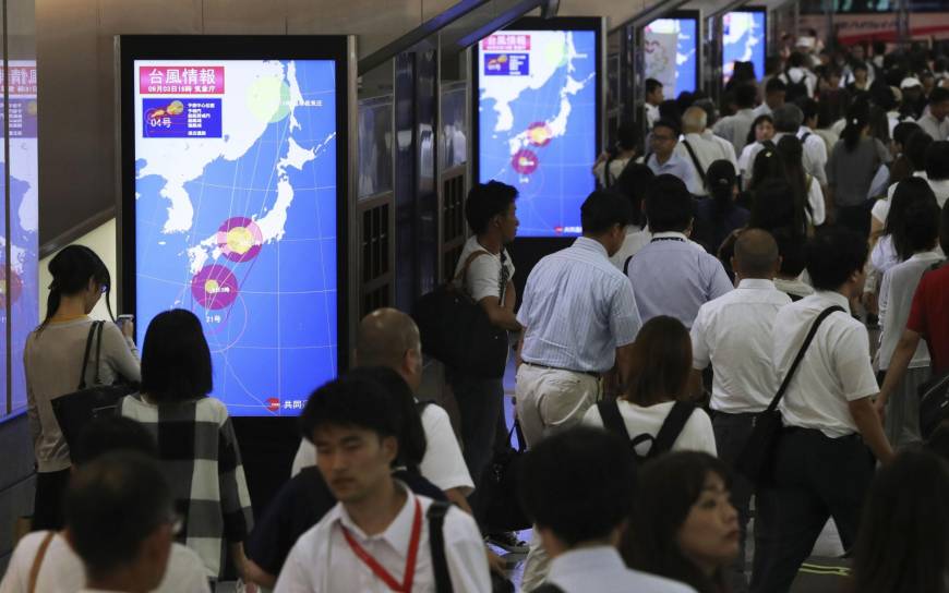 Monitors show the projected course of Typhoon Jebi at JR Osaka Station Monday night. Some train services in western Japan were suspended Tuesday as the powerful typhoon is on course to hit the region.