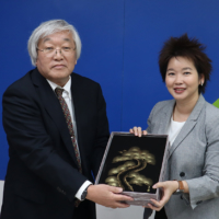 Tano exchanges a gift with the Executive Vice President of Thailand’s National Science and Technology Development Agency Uracha Ruktanonchai in September. | UEC