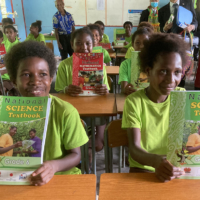 Students pose with math books received under a project for improving academic ability in elementary schools. | JICA